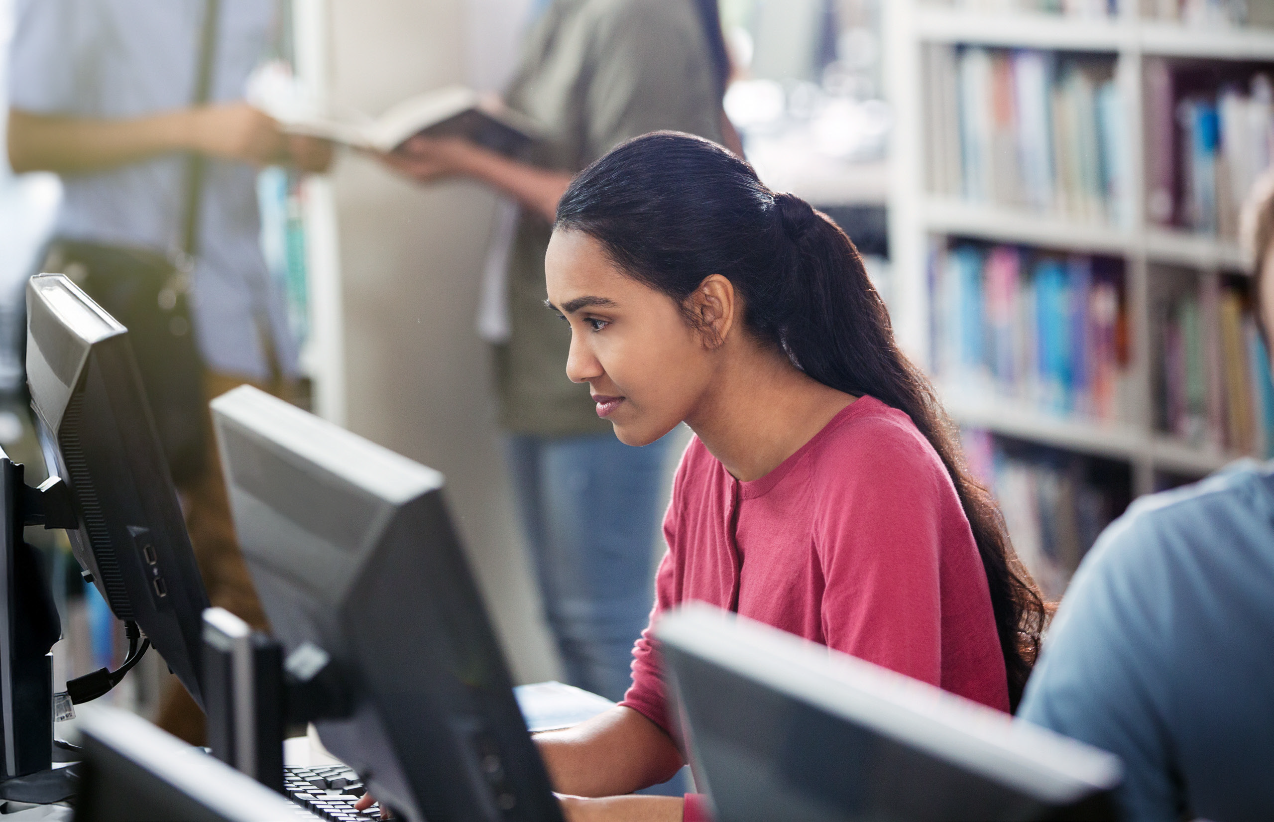 Teenage girl looking at a computer screen in a library